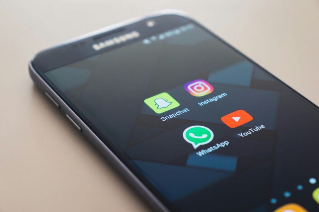 Black smartphone with various app icons displayed on the screen