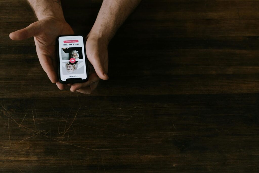 A person holding a phone with a dating app on the screen, showing a match with someone