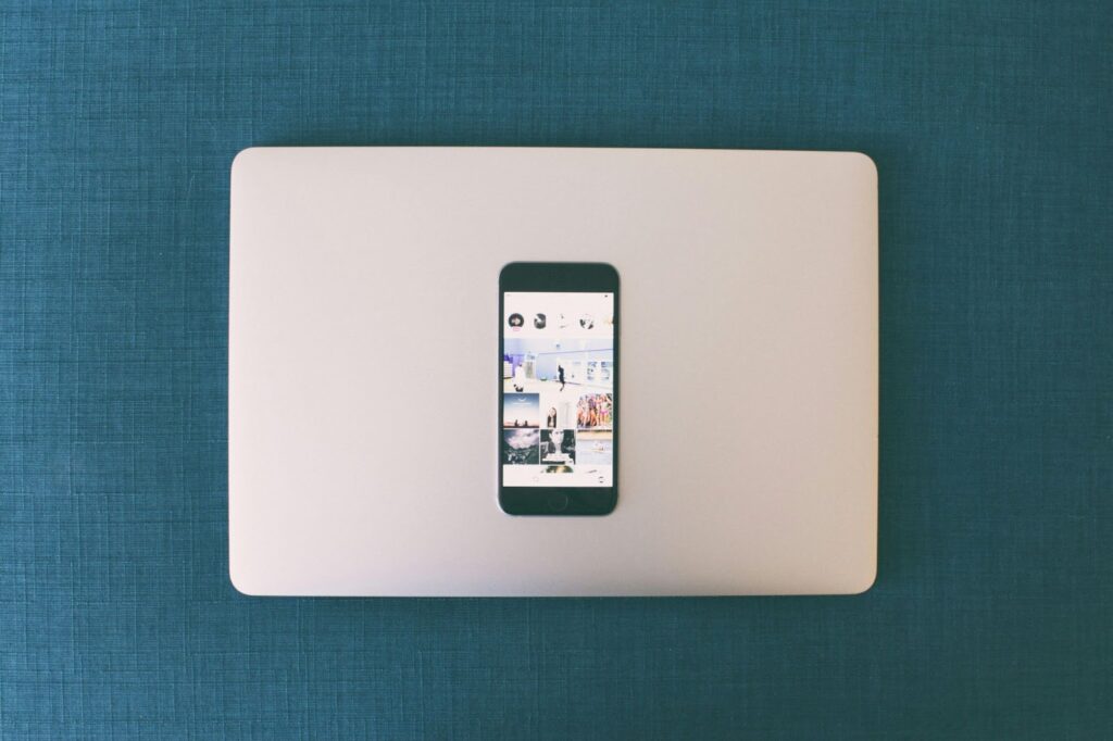 A smartphone with the Instagram app open, resting on top of a laptop